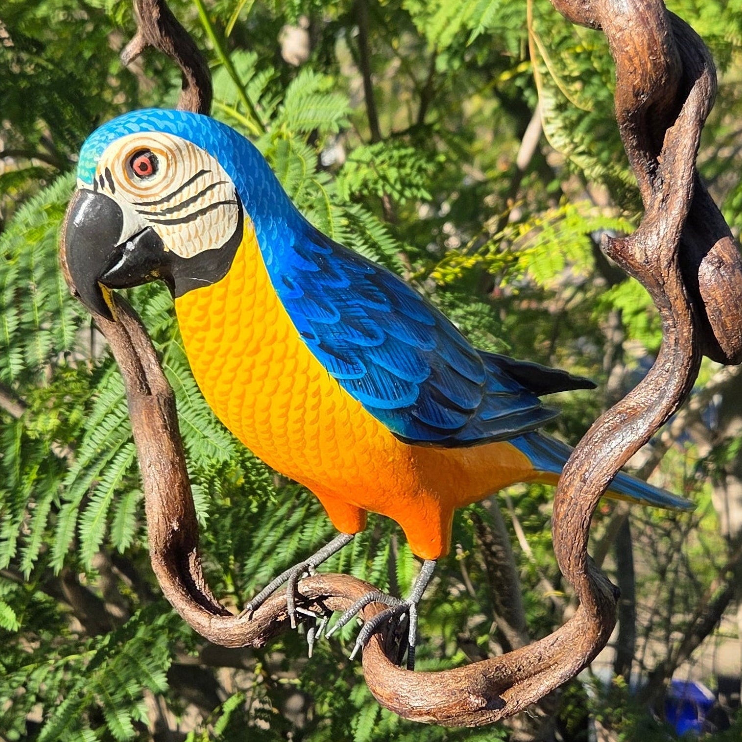 Blue and yellow macaw perched on a branch with green foliage in the background