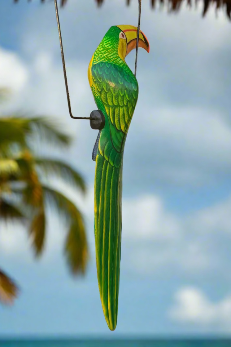 Decorative green parrot ornament hanging against a blue sky with clouds