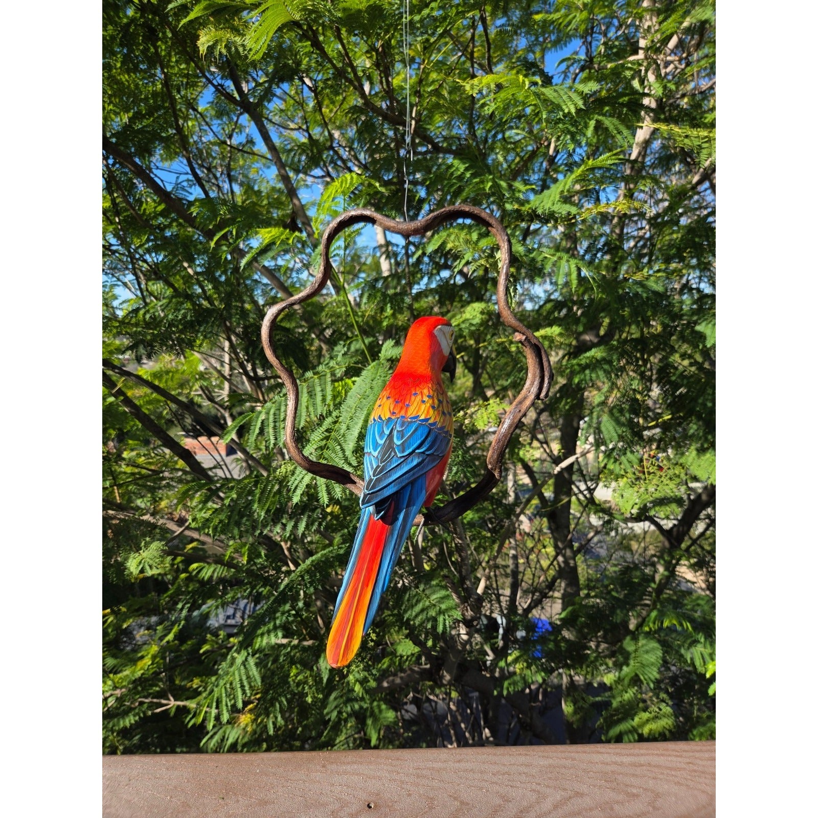 Colorful Macaw wooden parrot perched on a jungle vine against a tree background