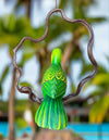 Decorative green parrot ornament hanging from a branch with a blurred natural background