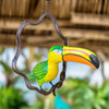 Decorative toucan figurine hanging on a branch with a blurred natural background