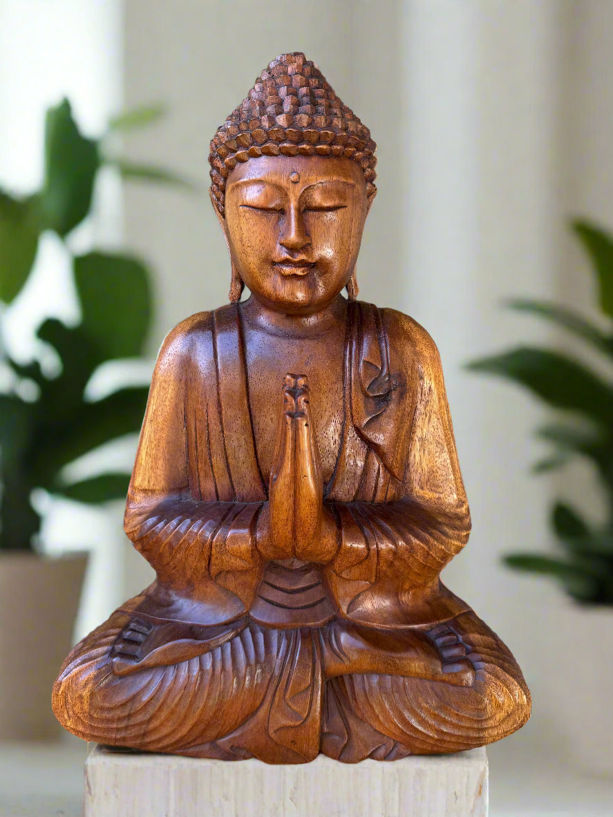 Wooden Buddha statue in a meditative pose with a blurred indoor background
