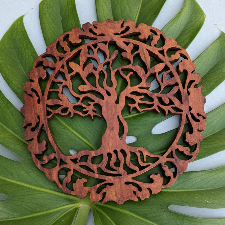 Wooden decorative circular piece with intricate carvings on a white background
