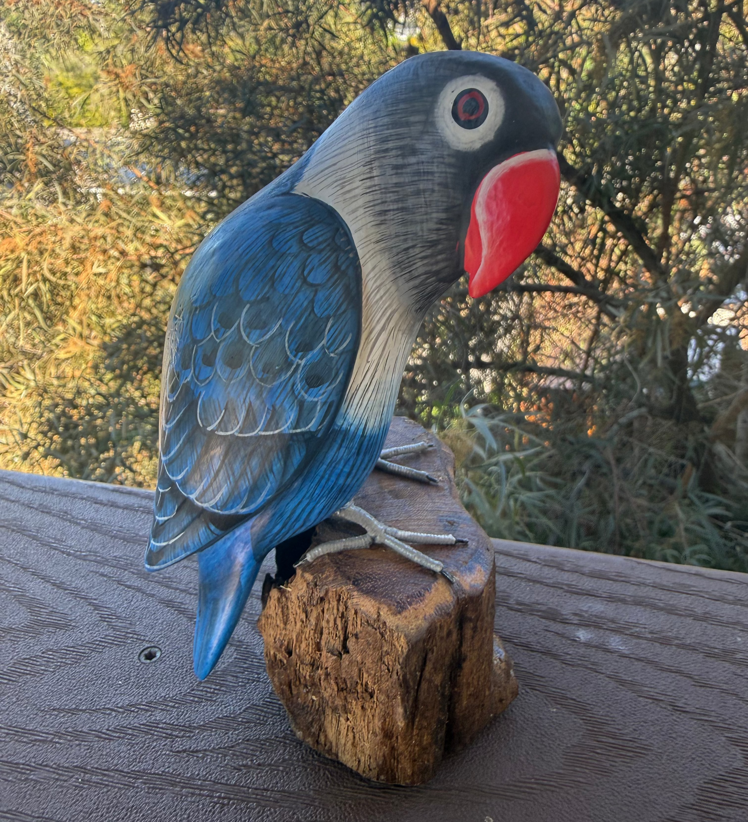 Carved wooden parrot figurine on a wooden surface with a natural background