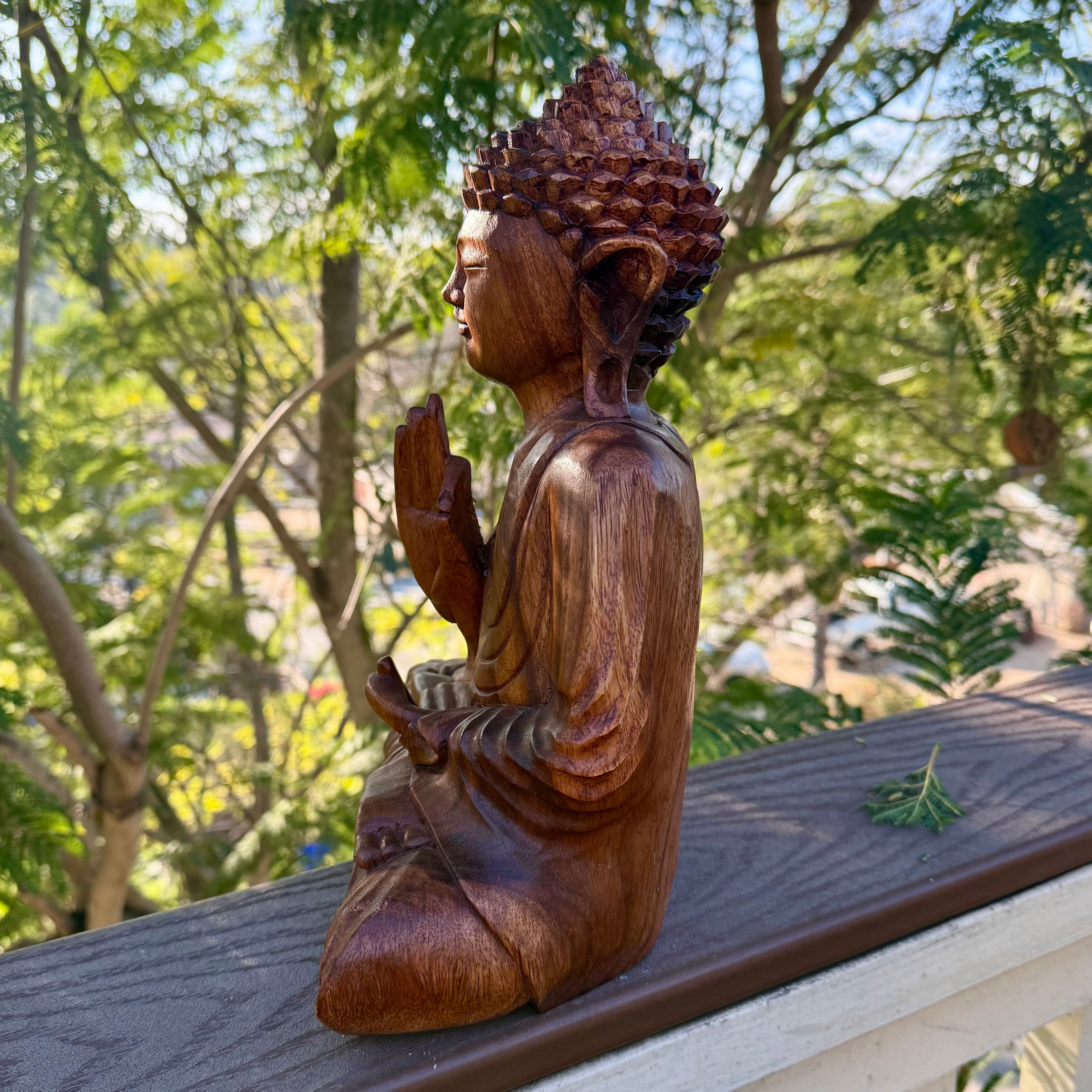Wooden Buddha statue on a railing with trees in the background