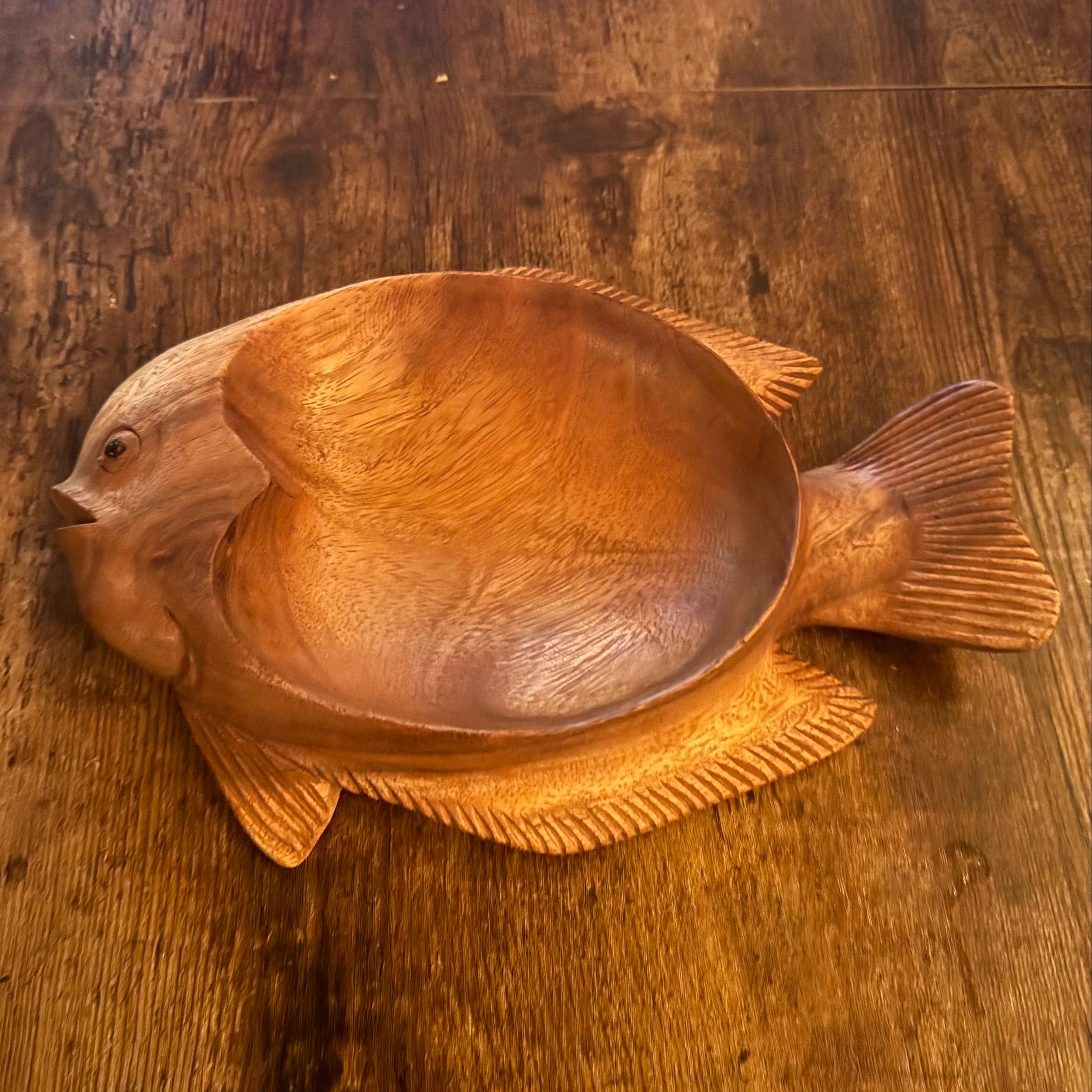 Wooden fish-shaped bowl on a wooden surface