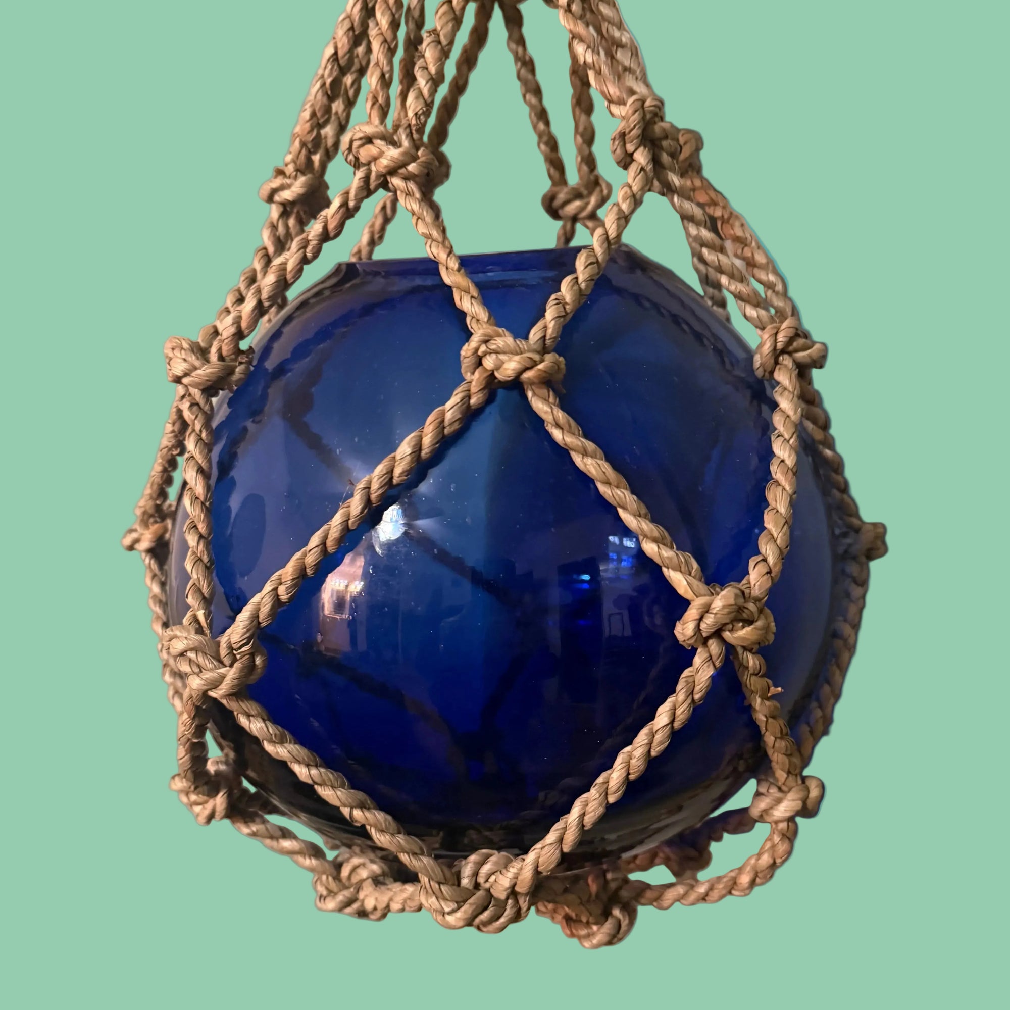 Blue buoy with rope netting on a teal background