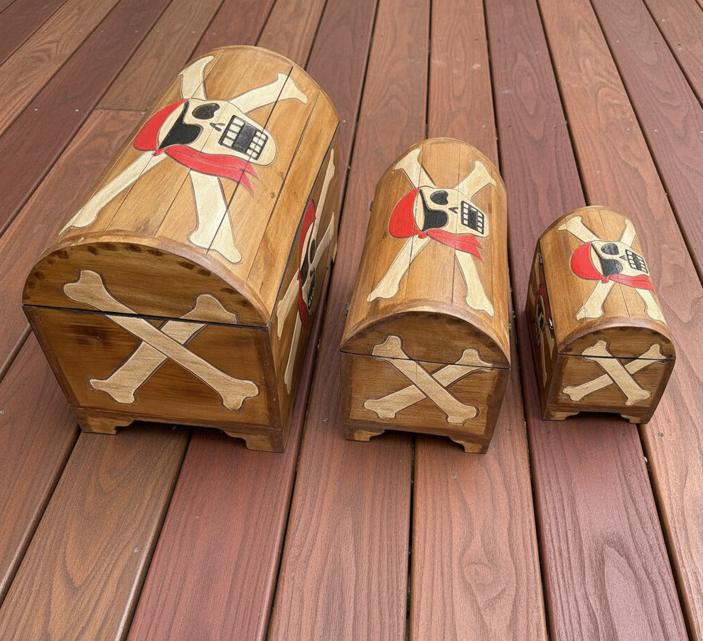 Three wooden boxes with pirate-themed designs on a wooden surface