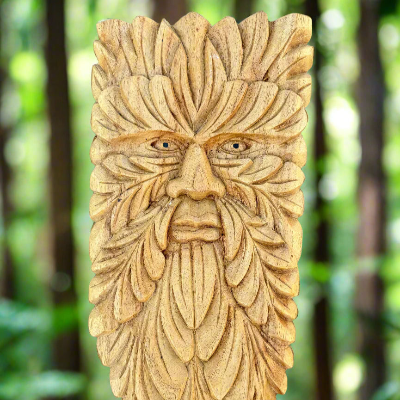 A hand-carved wooden wall decor depicting a green man figure with leaf-like features and a face with eyes and a mouth.