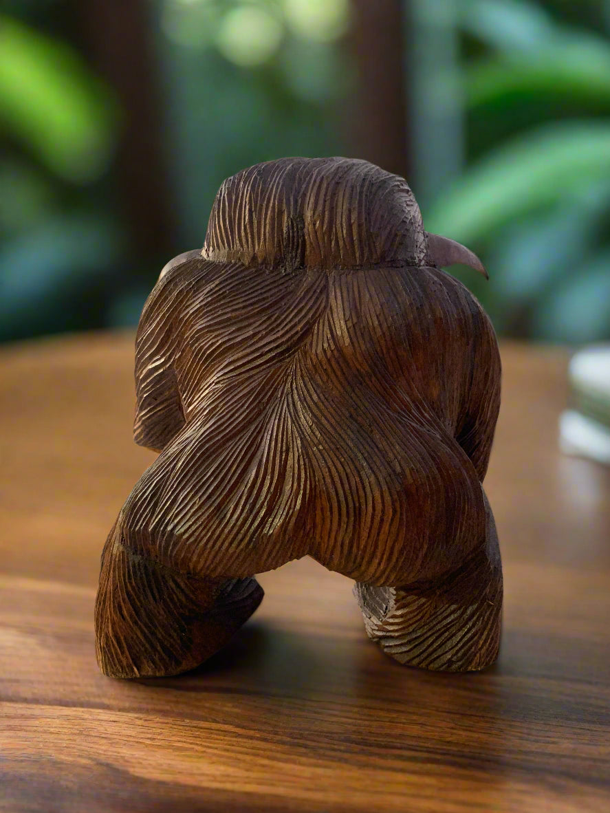 Abstract dark wooden sculpture with flowing grain patterns on a wooden table
