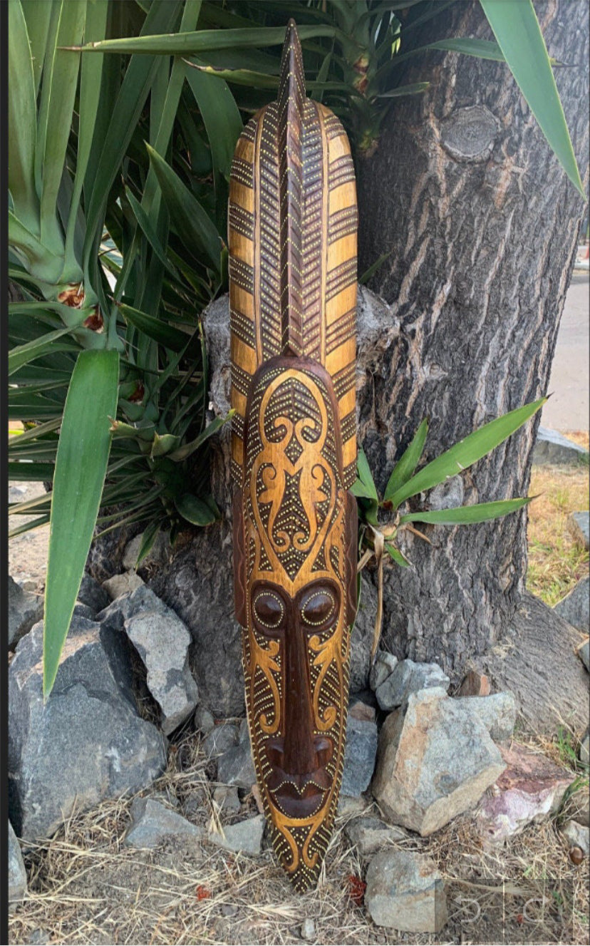 Carved wooden tribal mask with geometric patterns on a tree trunk