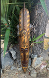 Carved wooden tribal mask with geometric patterns on a tree trunk