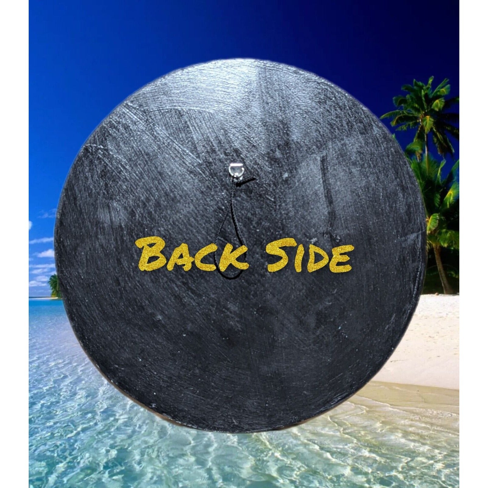 Black circular back of a drum on a tropical beach with palm trees and the words BACK SIDE in yellow