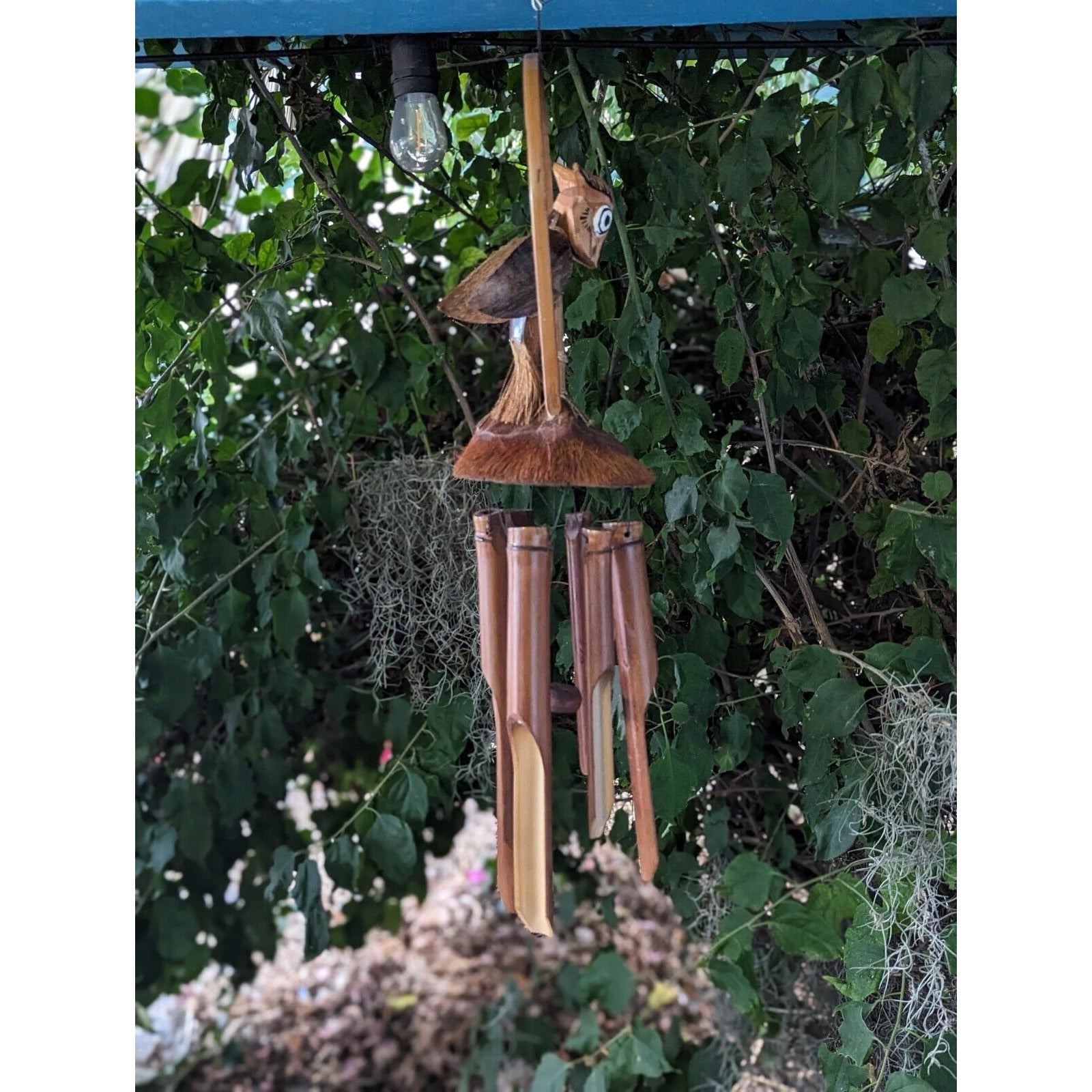 outdoor bamboo wind chime with spoon-shaped tubes hanging among green leaves