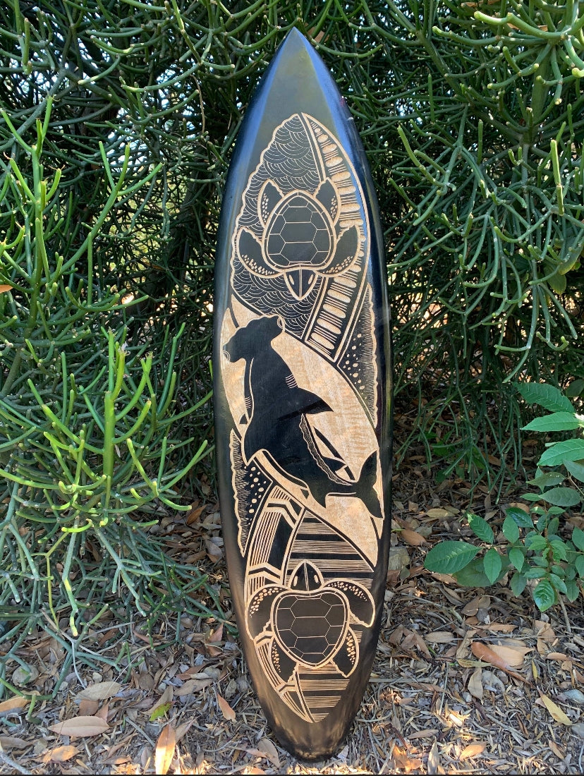 Carved surfboard featuring a black bear silhouette amid geometric patterns and waves