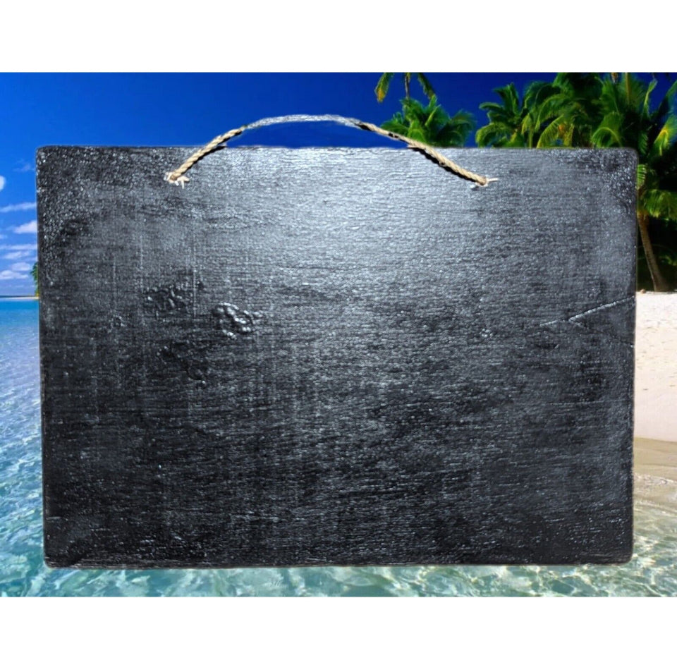 black slate sign with rope handle on a tropical beach