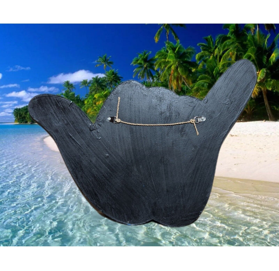 Black wooden hand-shaped sign with a rope, on a tropical beach with palm trees and clear turquoise water.