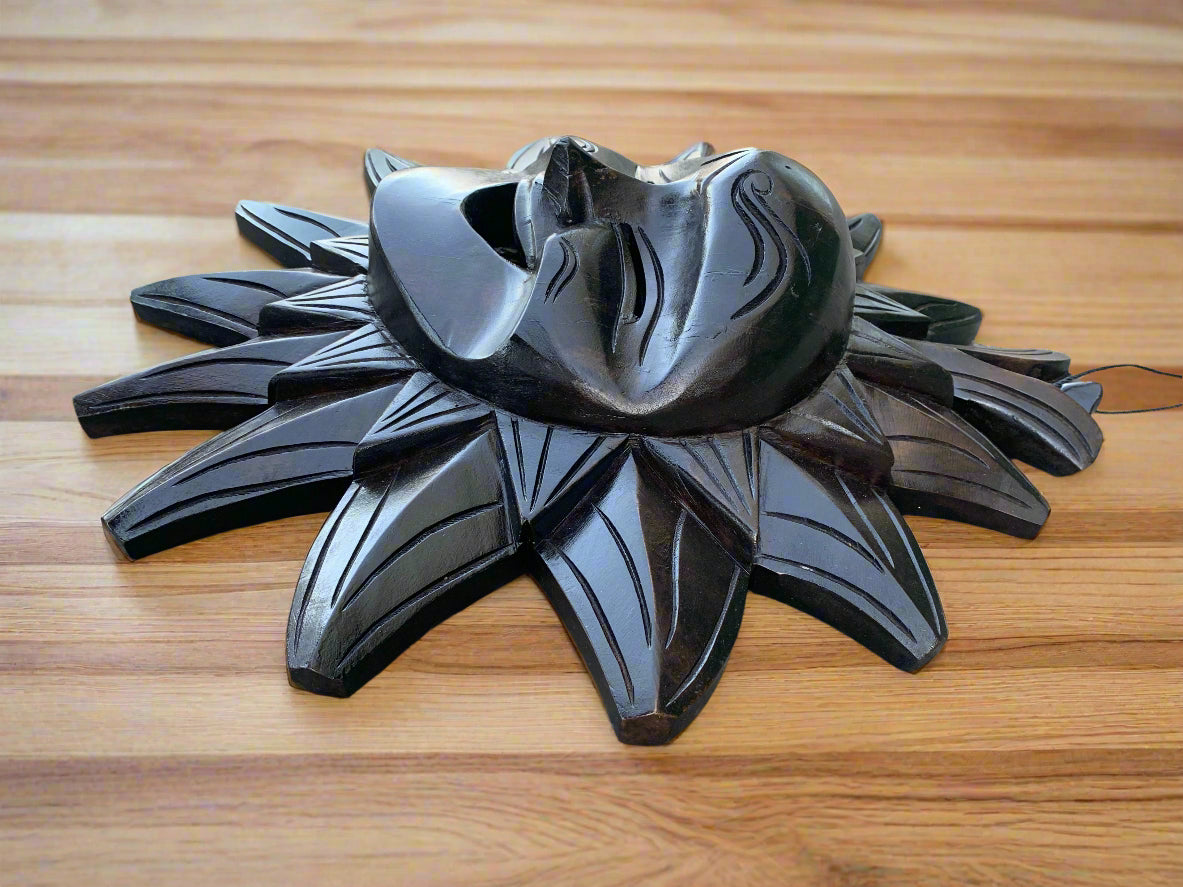 Glossy black wooden sunburst sculpture with layered petal-like rays.