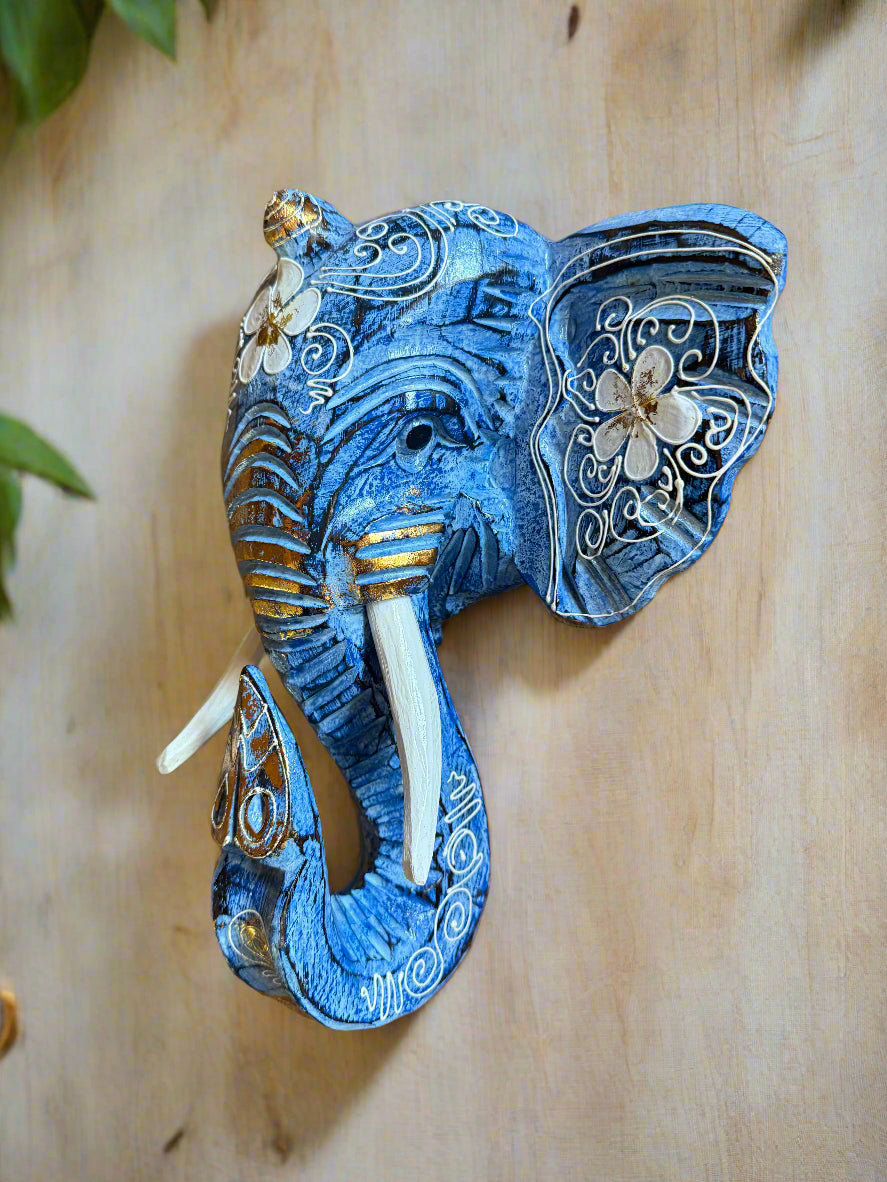 Blue decorative elephant sculpture with white floral patterns on a wooden background