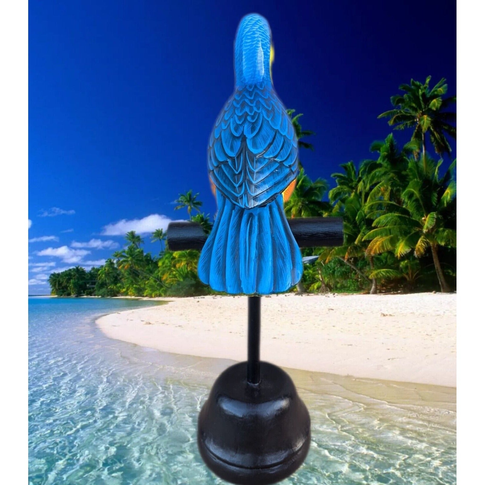 Blue parrot statue on a stand at a tropical beach with palm trees