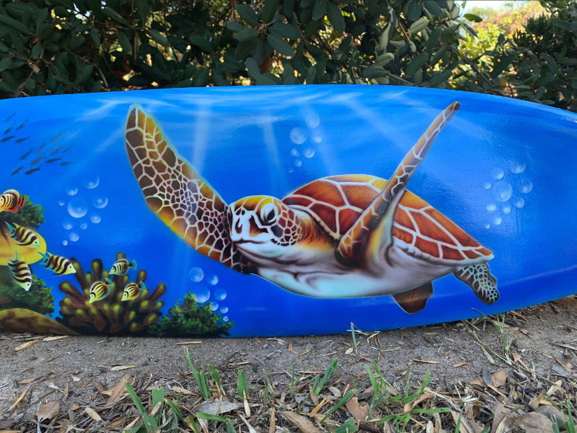 Blue inflatable pool float with a colorful sea turtle mural swimming among coral and fish