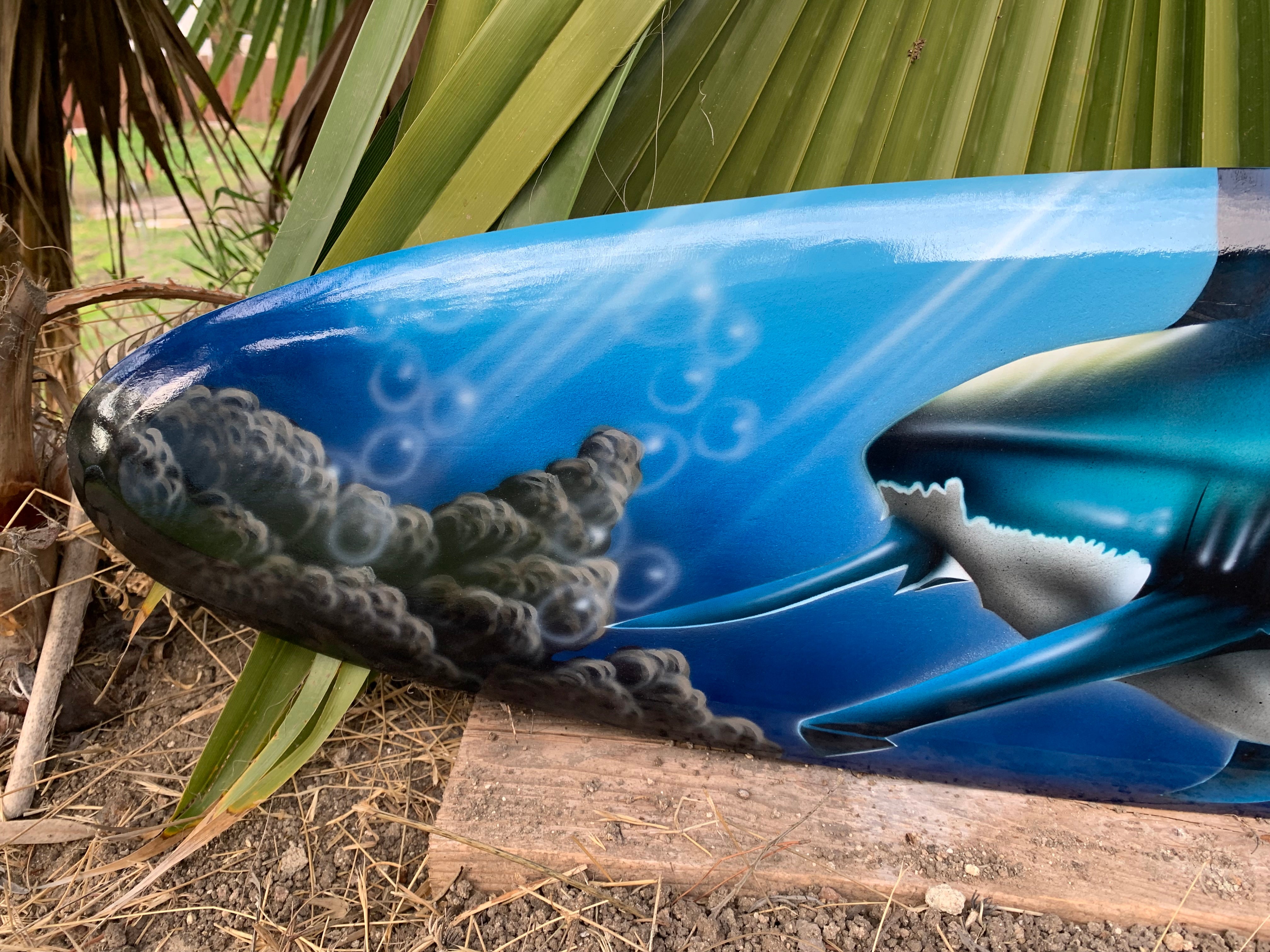 Blue-painted surfboard detail with waves and bubbles