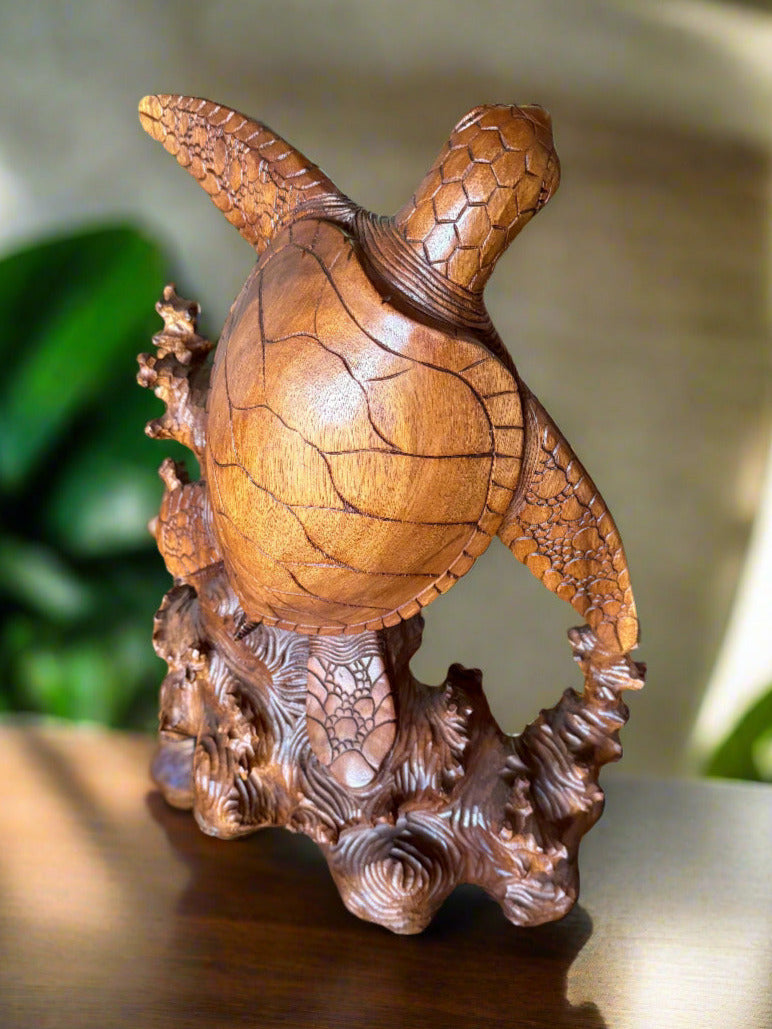 Bronze turtle statue with a cracked shell perched on a carved coral base