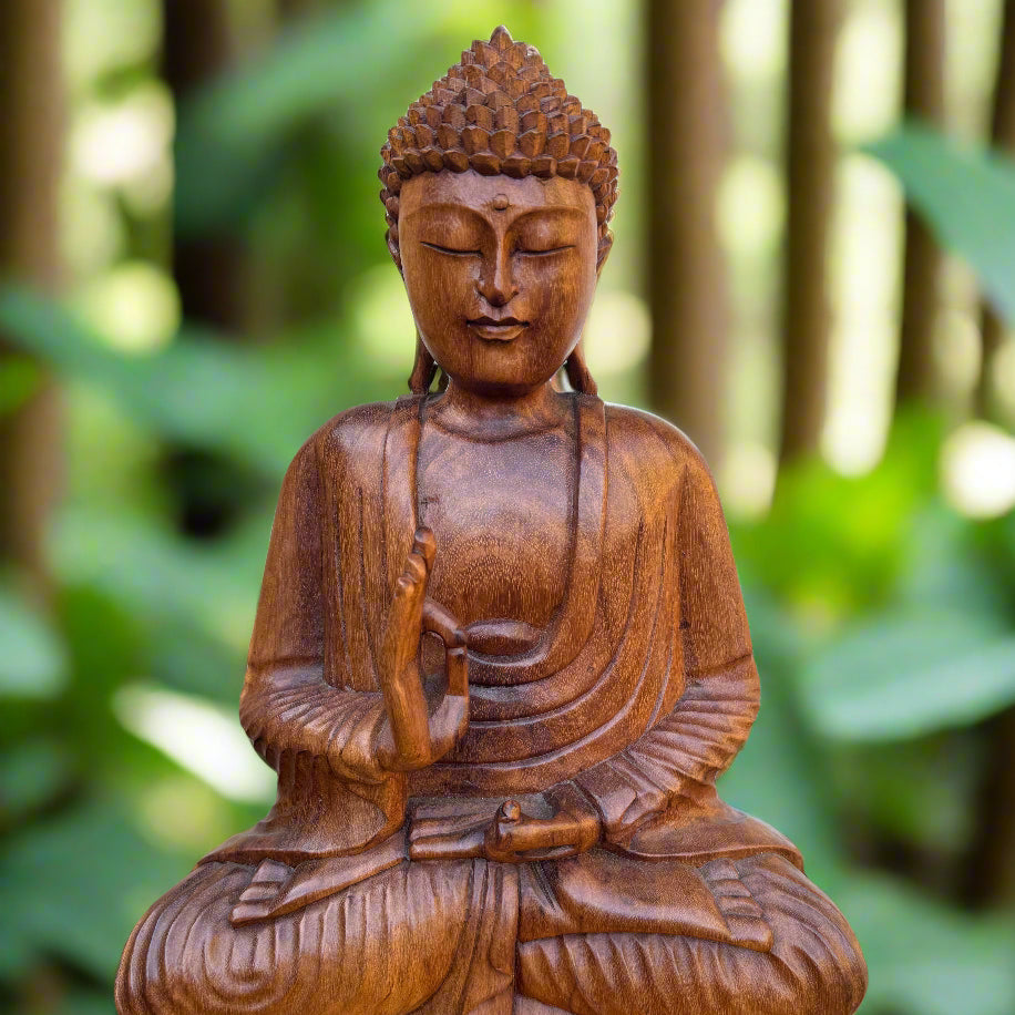 A handcrafted mahogany wood statue of a meditating Buddha, sitting cross-legged, with a serene expression on his face, set against a blurred background of a garden.