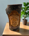 Buddha head carved into a wooden log on a table