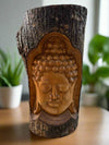 Carved wooden Buddha face on a log stump
