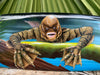 Cartoon sea monster mural featuring a brown, scaly creature with sharp claws emerging from water.