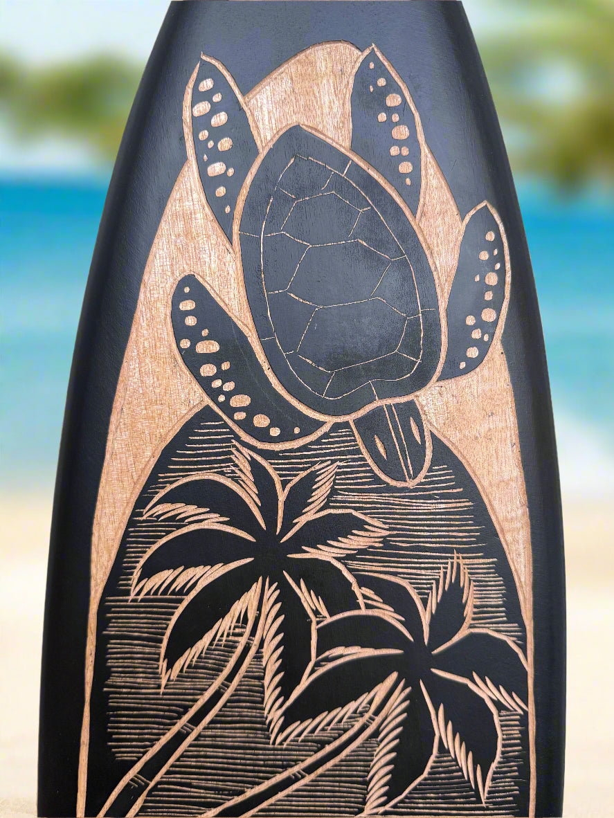 Carved sea turtle with palm trees on a dark surface