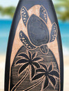 Carved sea turtle with palm trees on a dark surface