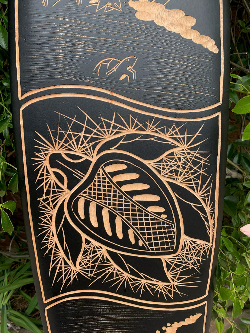 Carved wooden panel showcasing a turtle-shell relief surrounded by a spiky circular motif and leaf accents