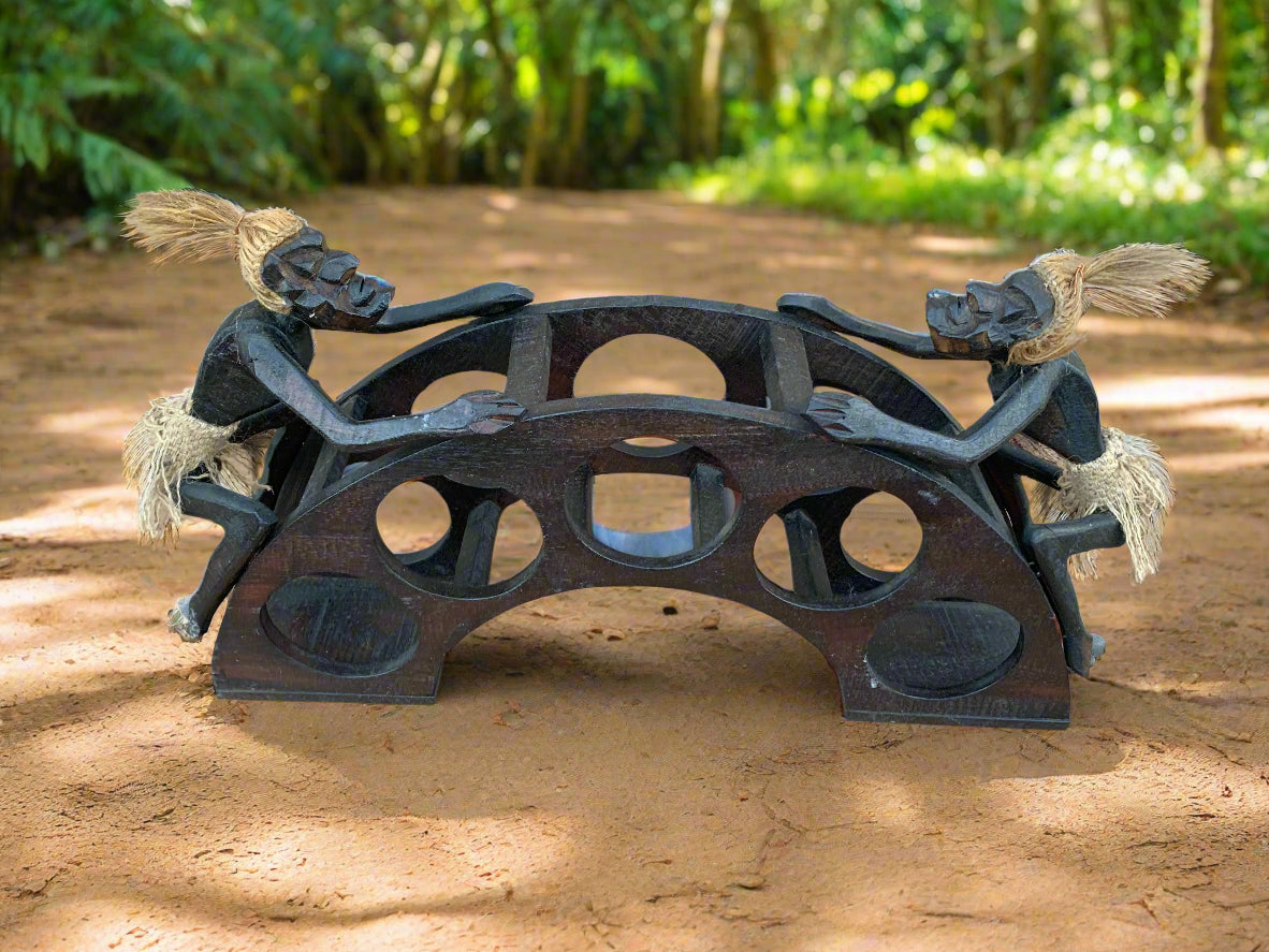 Two carved wooden figures leaning on a decorative arch bridge outdoors