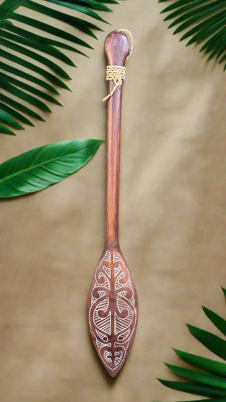 Carved wooden paddle with rope-wrapped handle and decorative tribal pattern