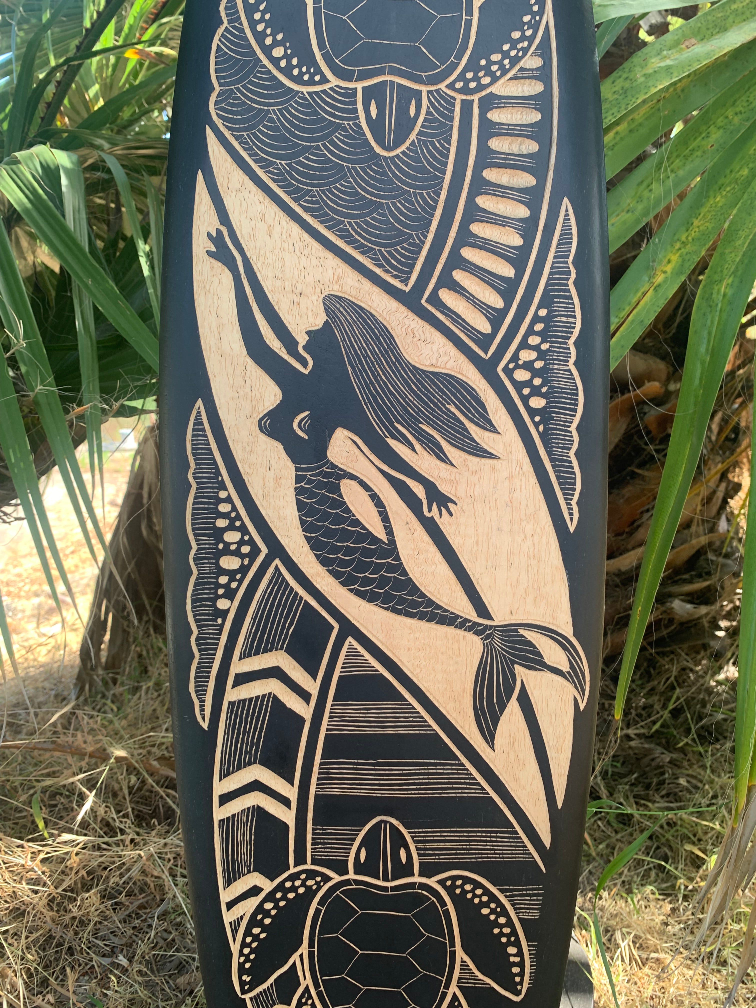 Carved wooden post with a mermaid-like figure and sea-motif patterns.