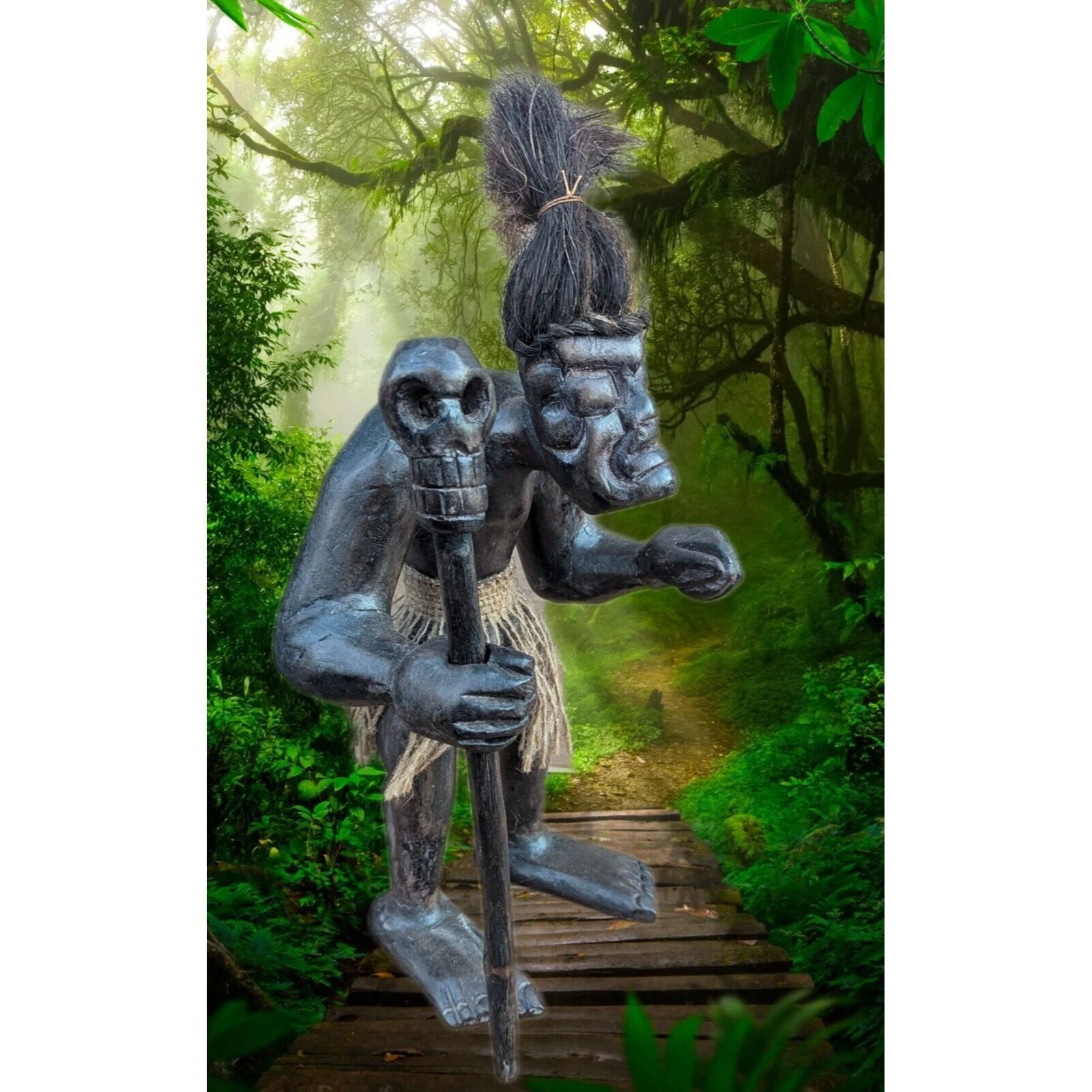 Carved wooden tiki statue holding a spear in a lush jungle path