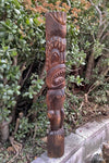 Carved wooden totem pole with abstract faces in a garden setting