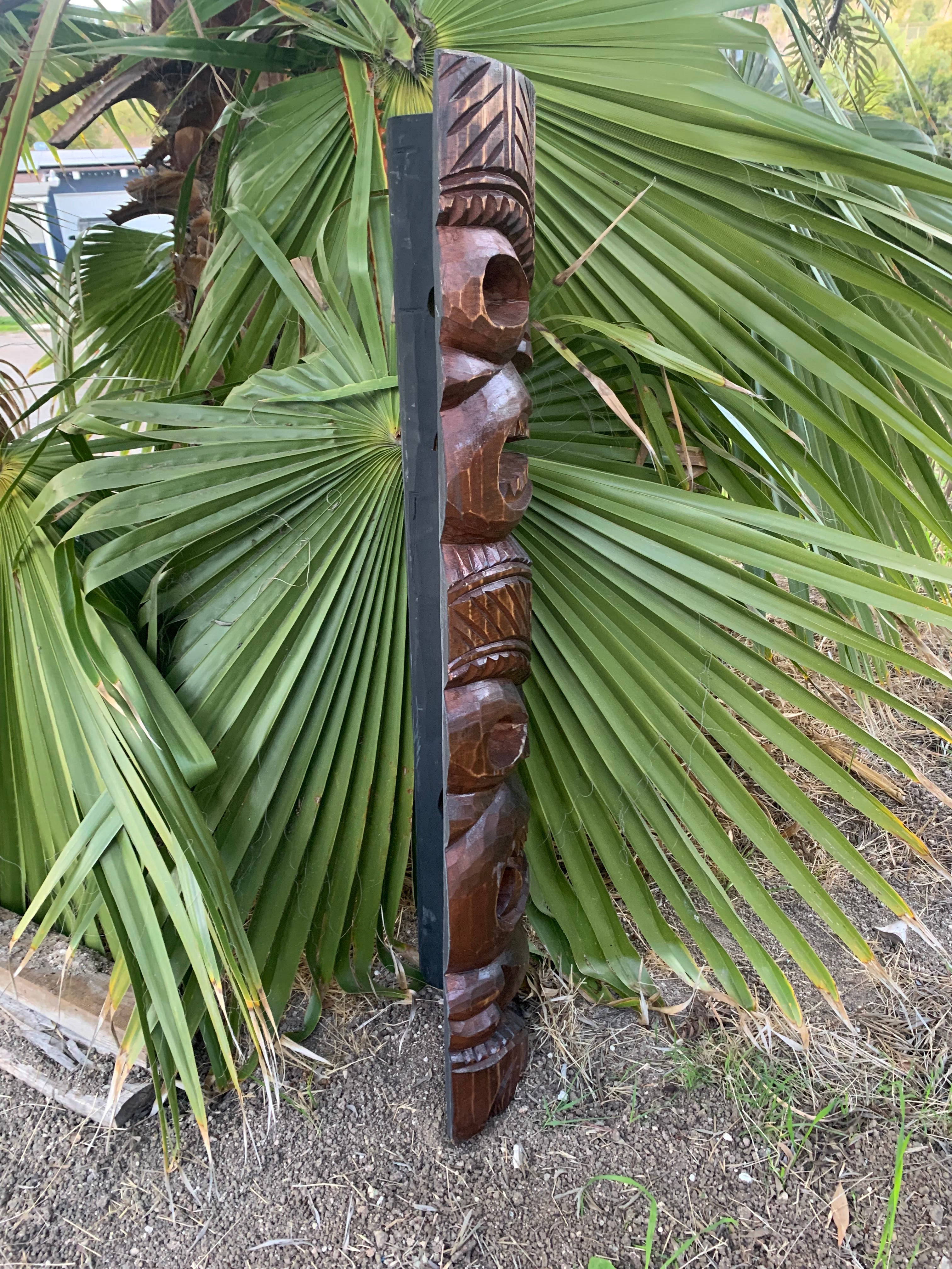 outdoor carved wooden totem pole beside palm leaves