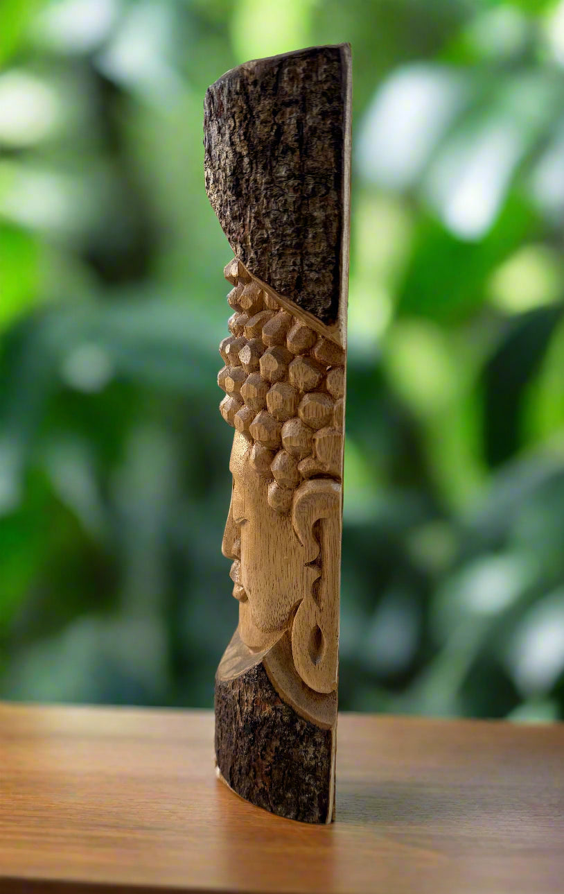 Carved wooden totem featuring a profile face and honeycomb texture, outdoors with green foliage in the background