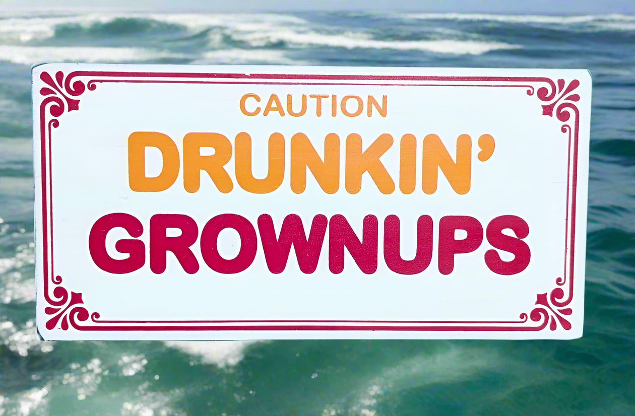 Caution Drunkin' Grownups sign over ocean waves