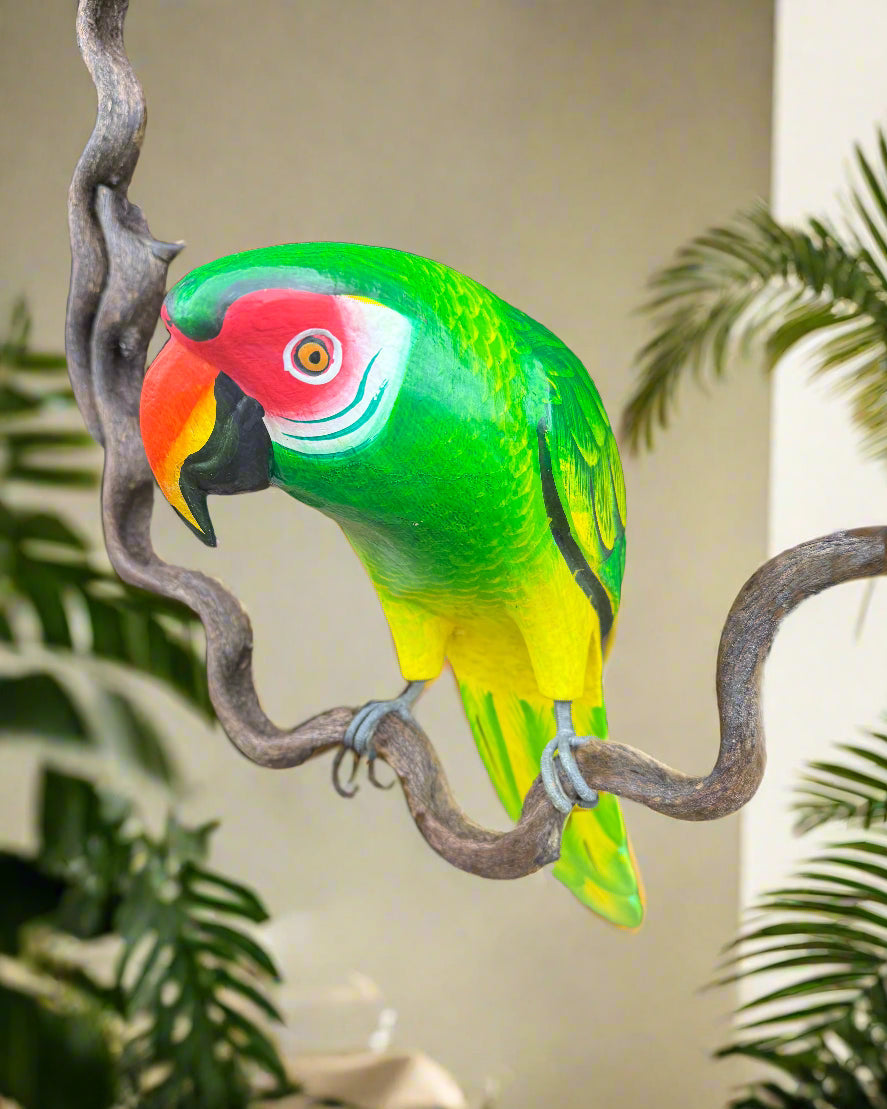 colorful macaw sculpture perched on a twisted branch, vibrant green body with red face and yellow belly