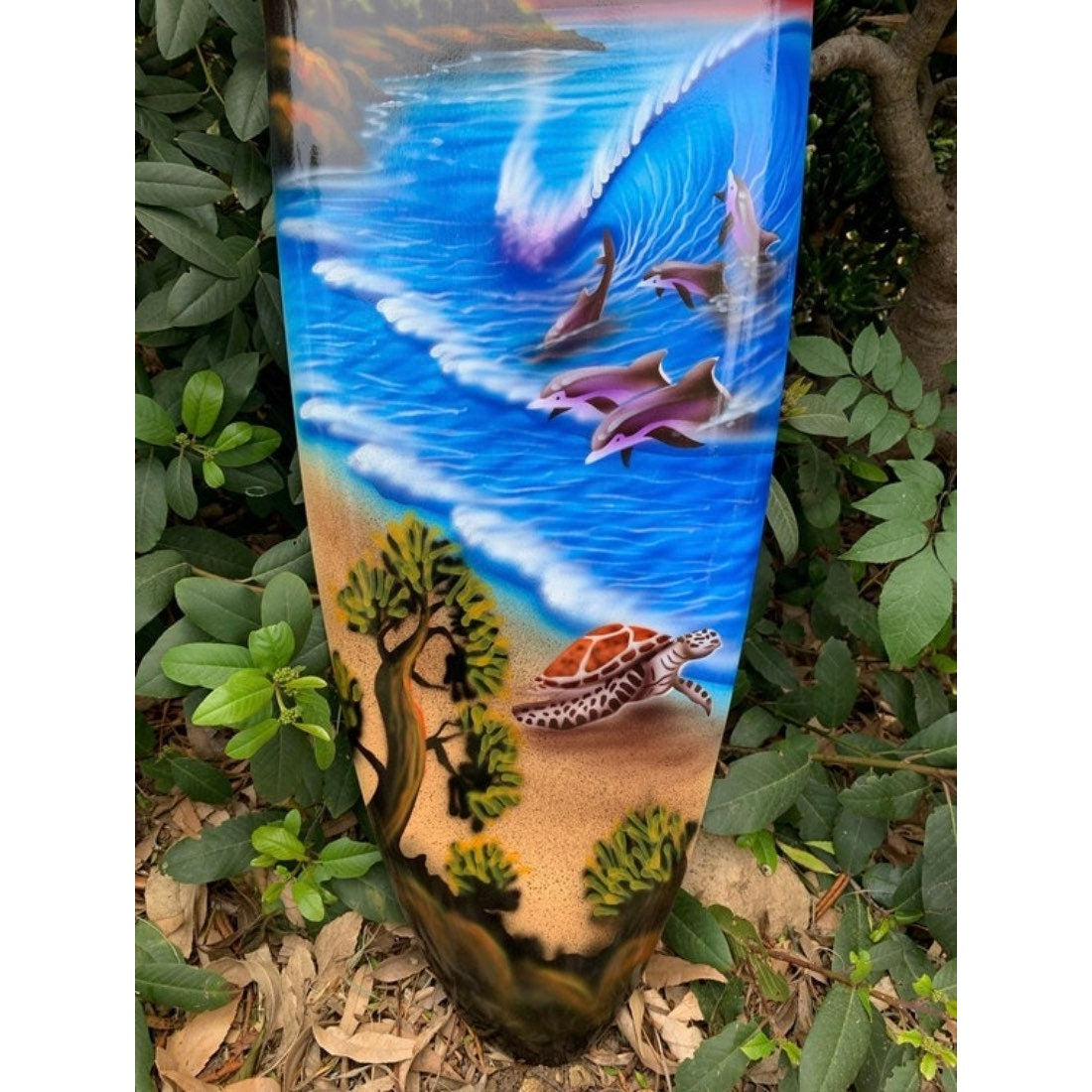 Painted ocean scene with dolphins and a sea turtle on a sandy shore