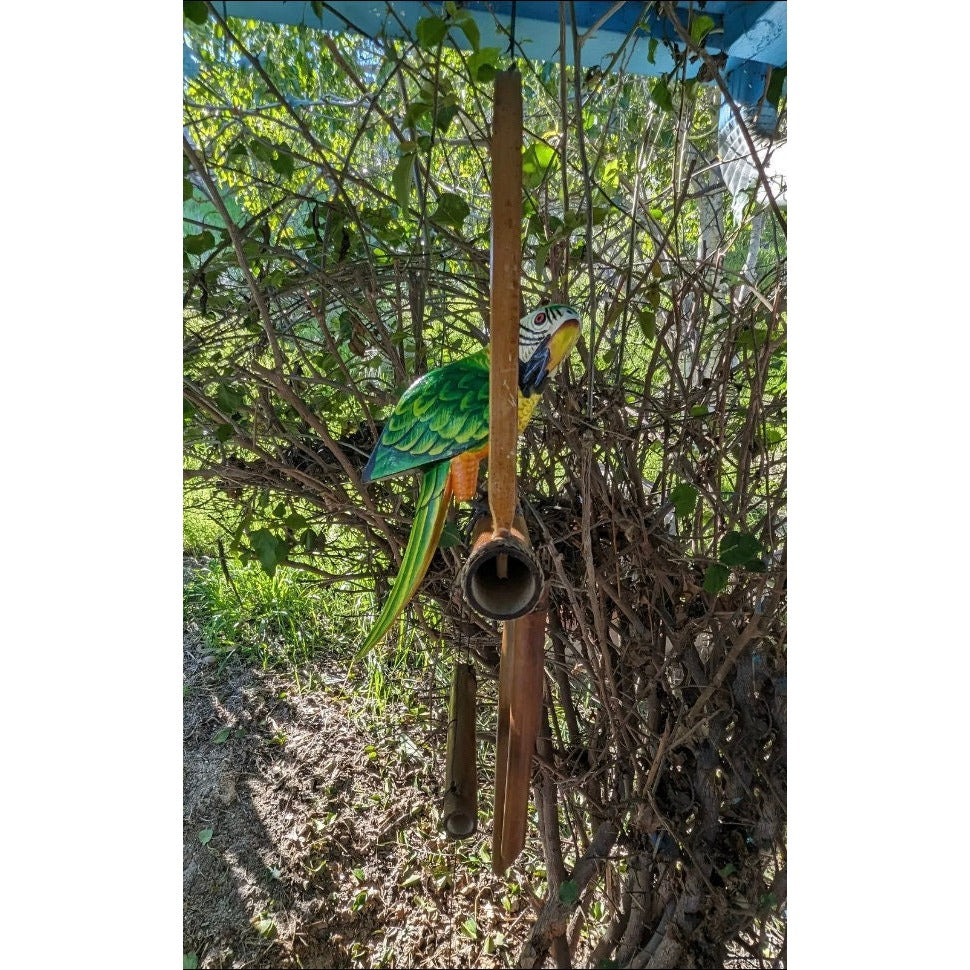 Colorful parrot garden sculpture perched on a wooden pole beside a hollow birdhouse