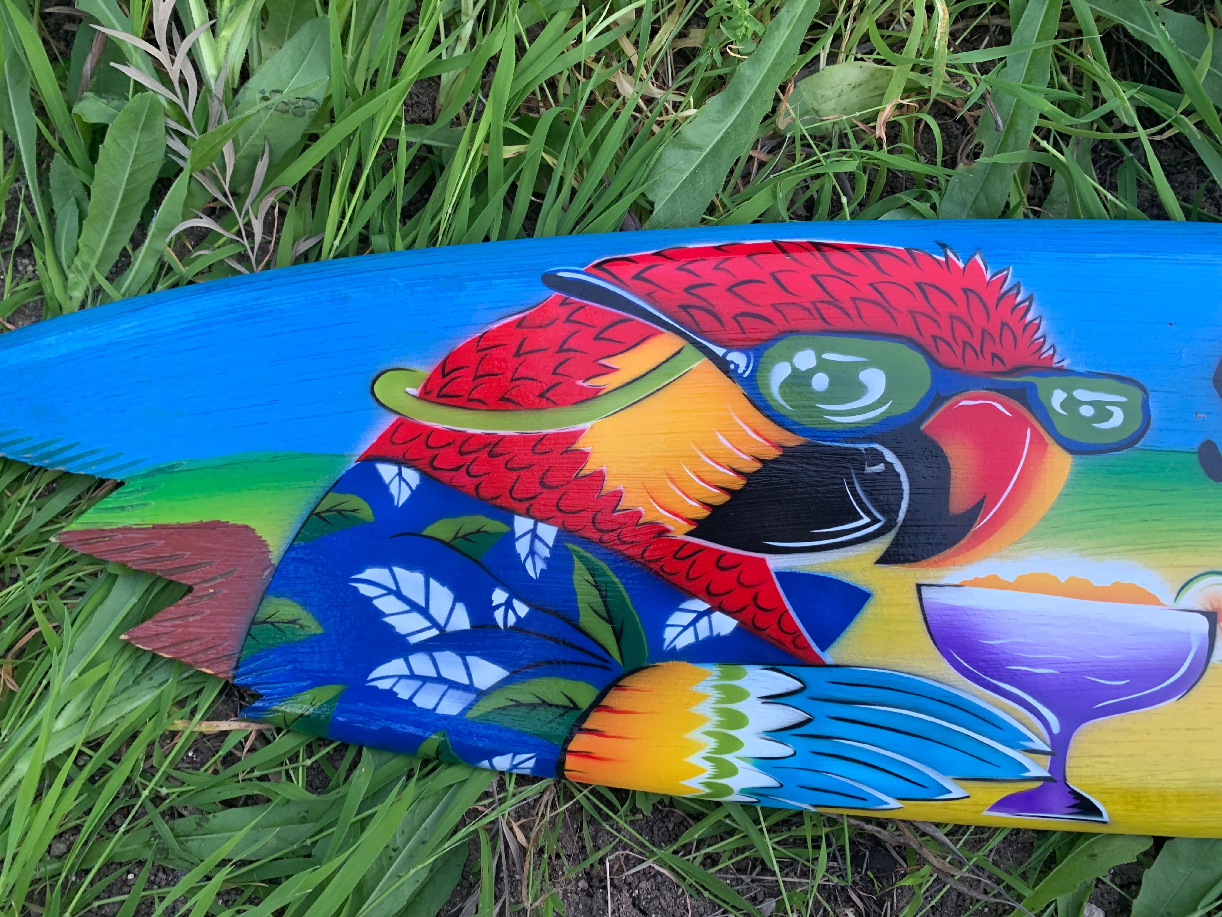 colorful parrot wearing green sunglasses on a blue painted board