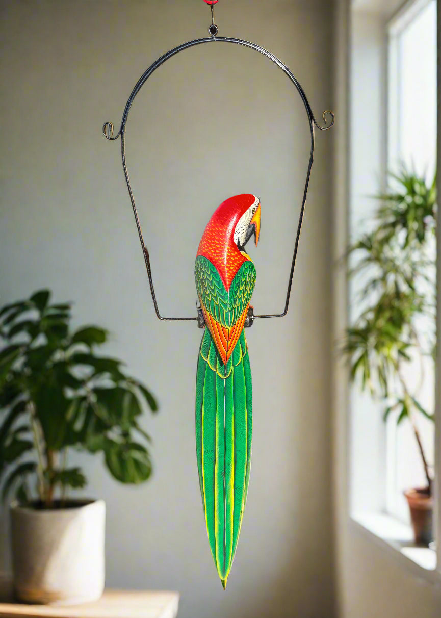 Colorful parrot-shaped wind chime hanging from a metal arch indoors
