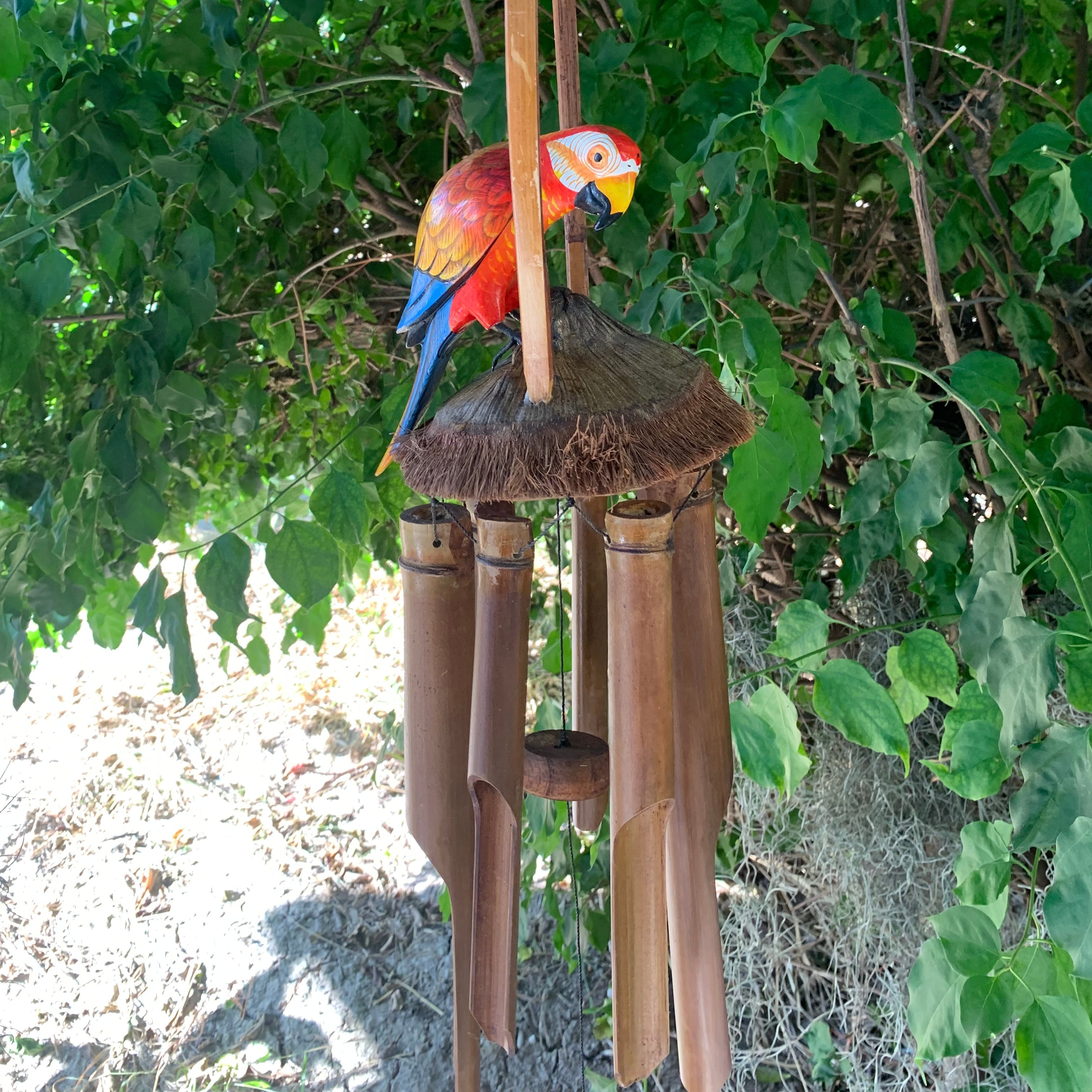 Colorful parrot wind chime with bamboo tubes hanging outdoors