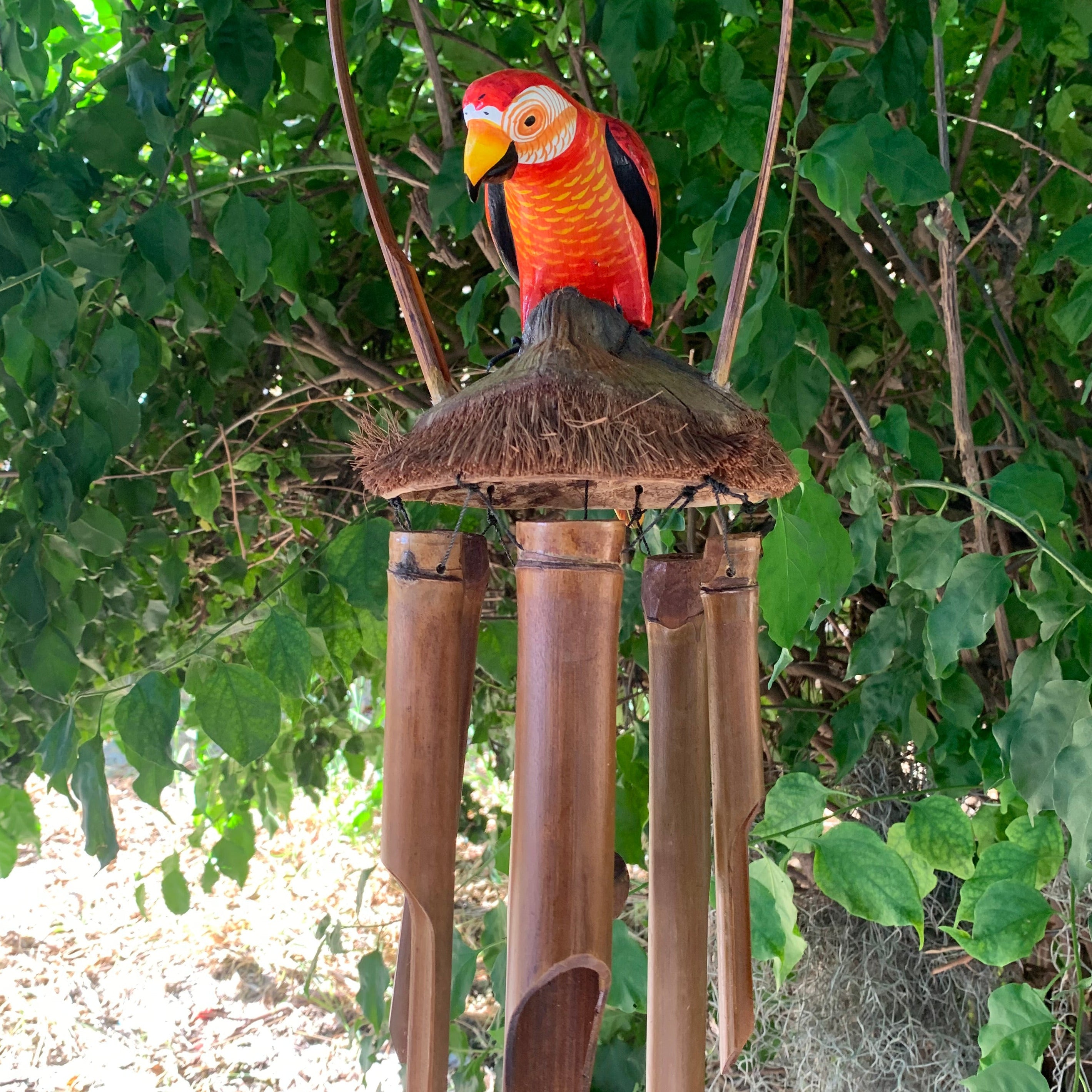 colorful parrot wind chime with bamboo tubes under a thatched roof