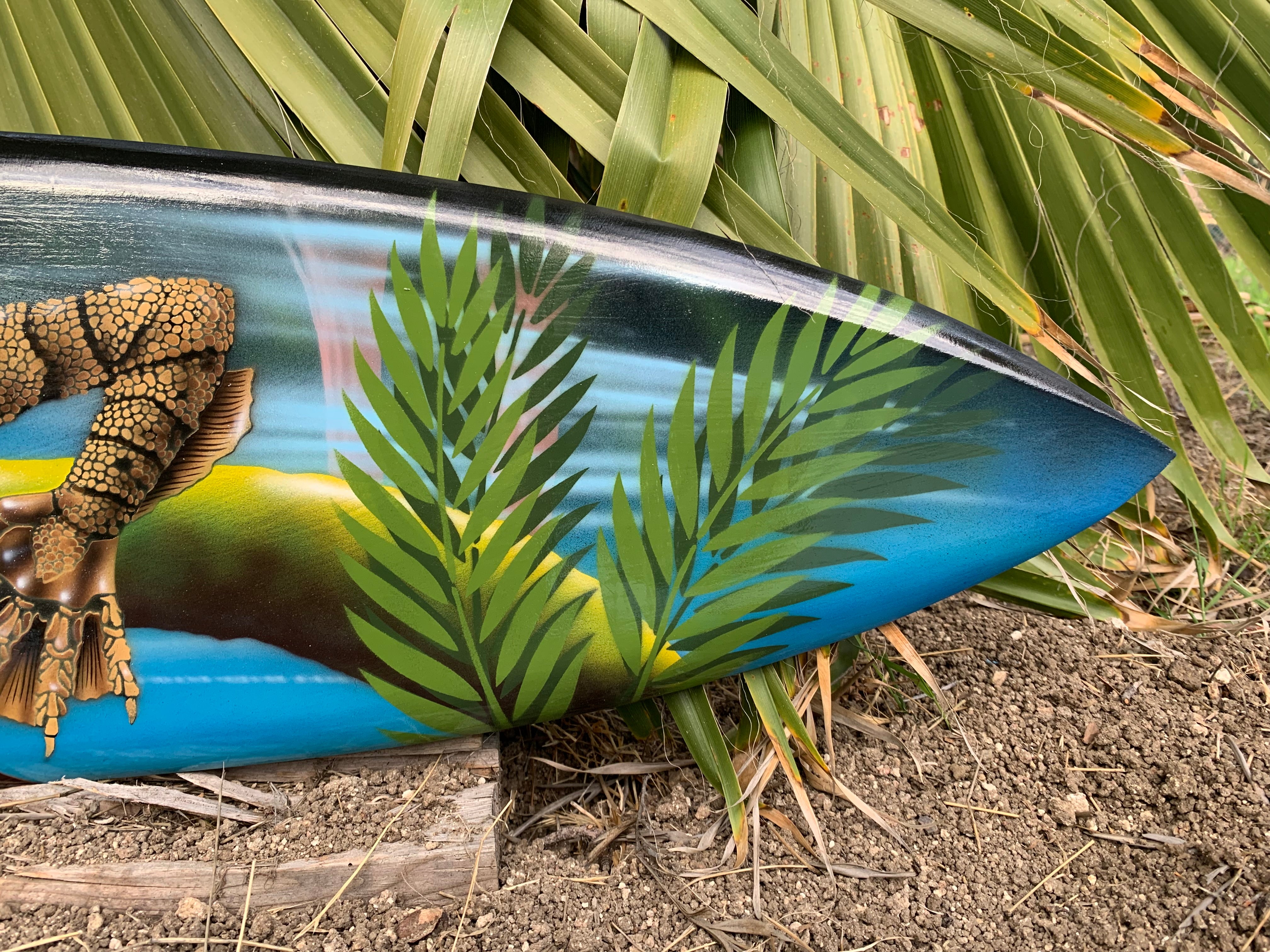 Surfboard with tropical palm leaf artwork and a brown reptile scale design.